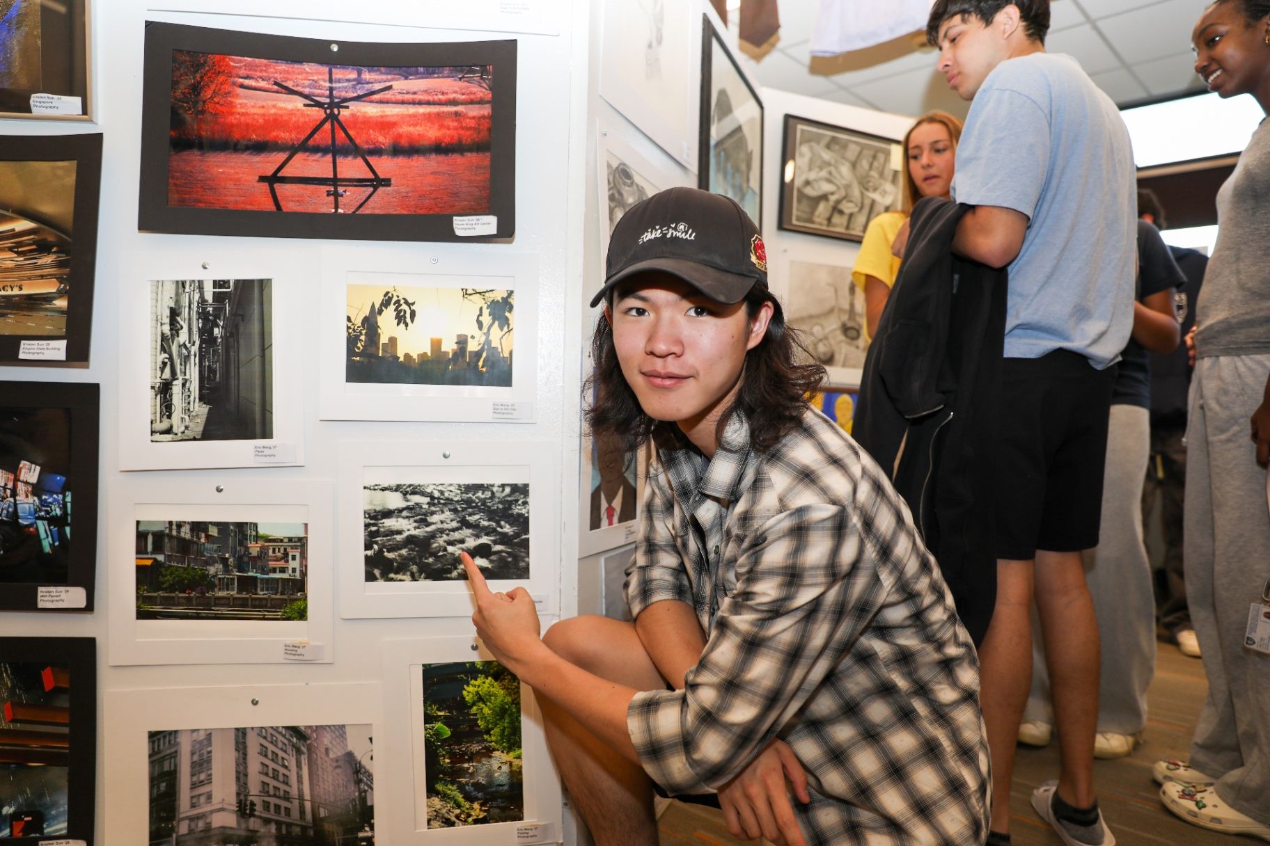 Student kneeling beside photography artwork at the annual showcase