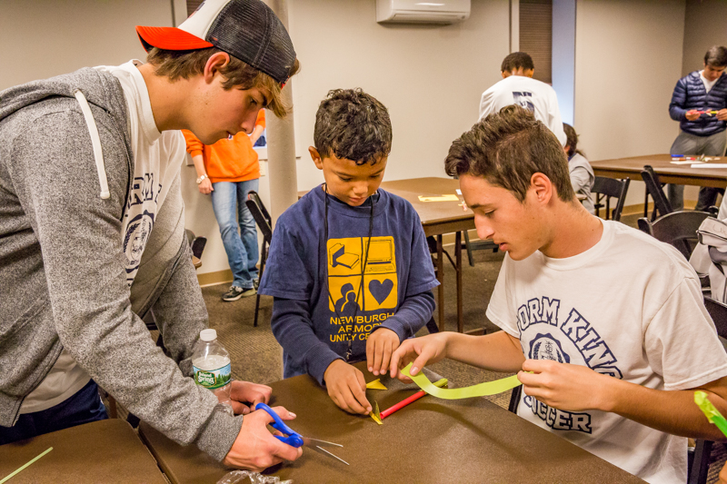 Eduardo Pena, left, and Daniel Moreno, right, help their student build a rocket with straws