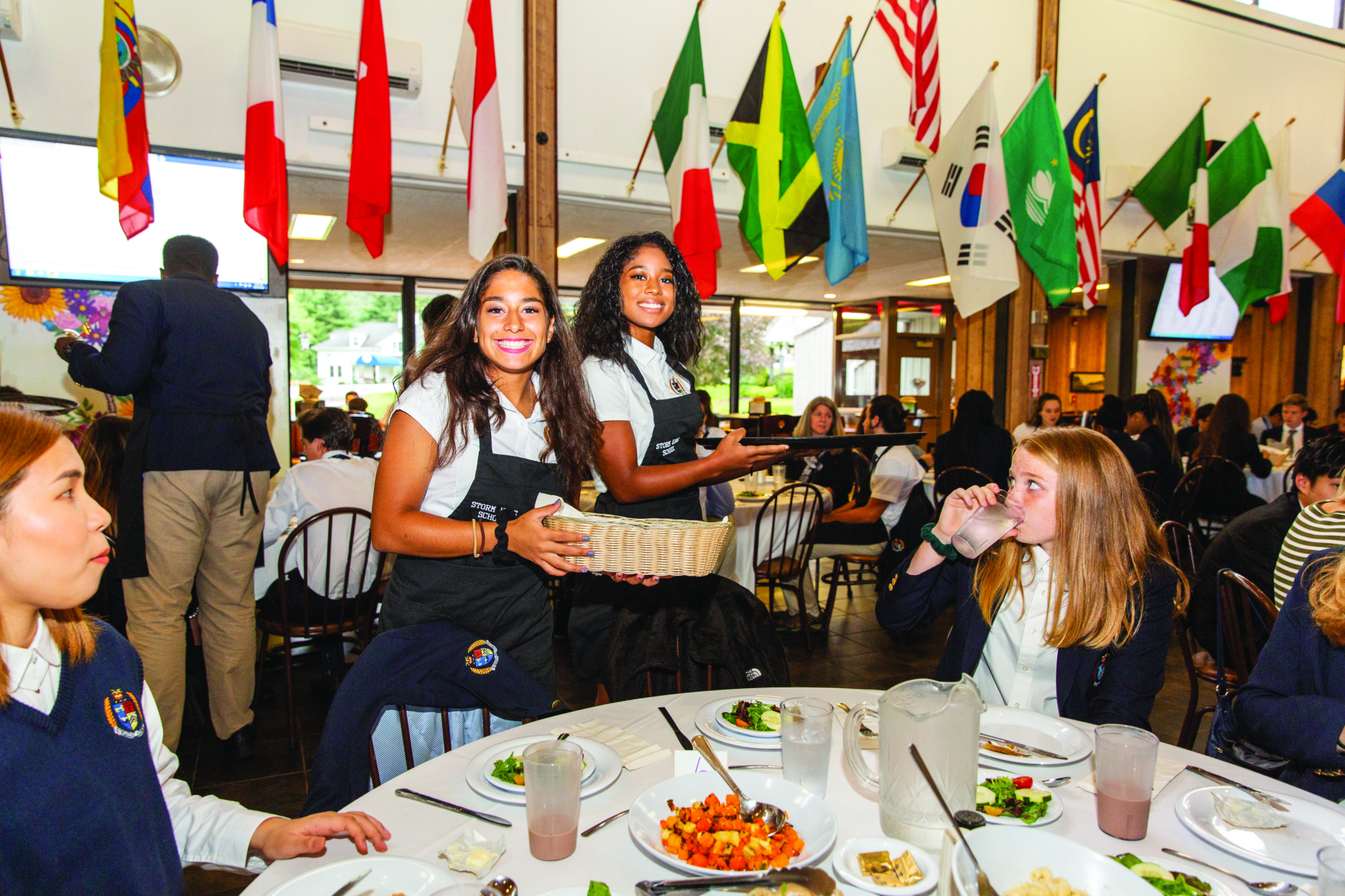 Students share a meal beneath the international flags in the dining hall