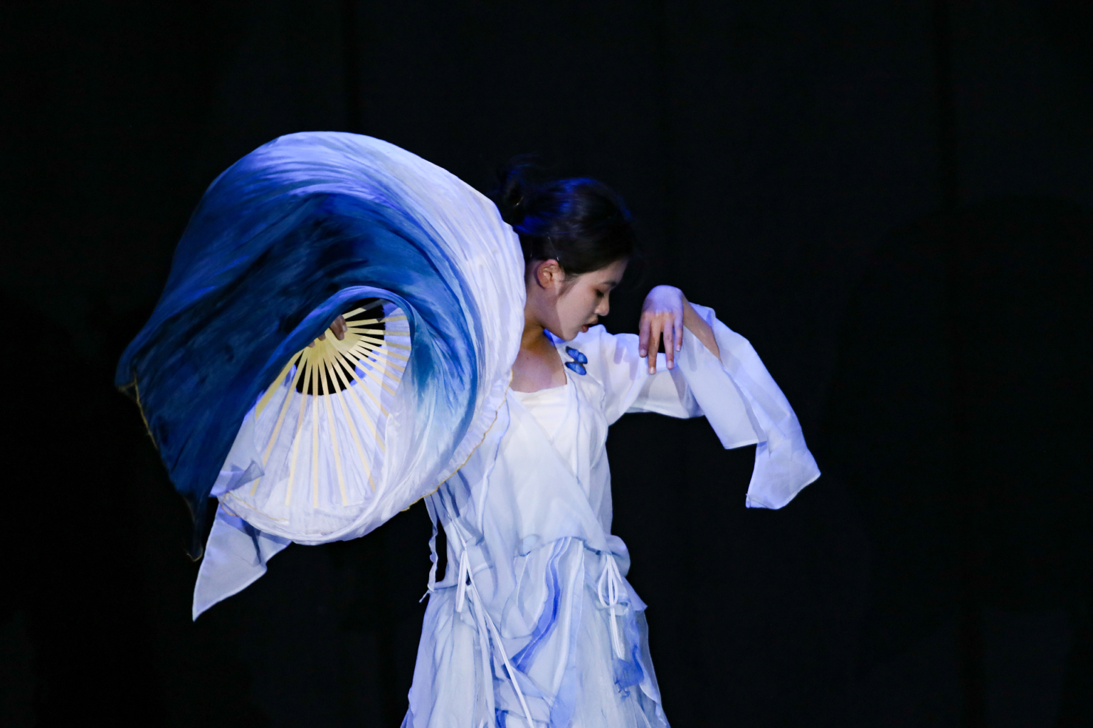 Student performing with blue and gold silk fans