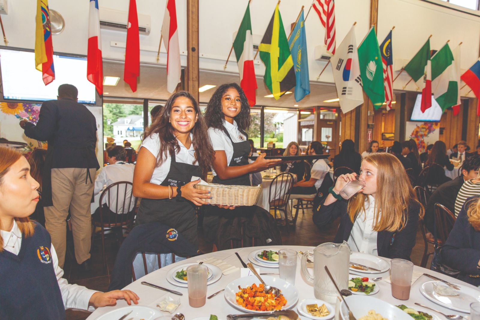 Students share a meal beneath the international flags in the dining hall