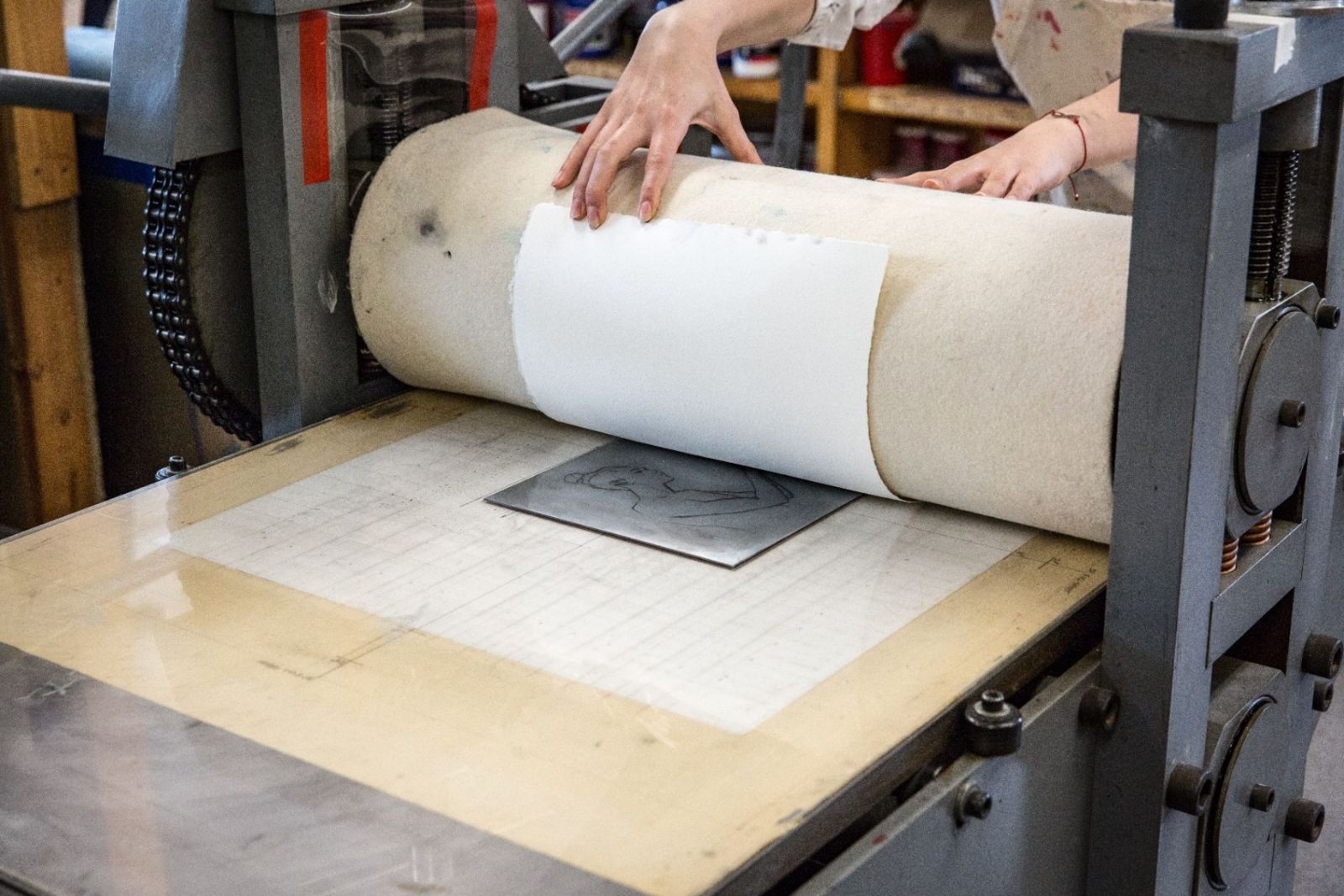 Student and instructor working at a printmaking press in the studio