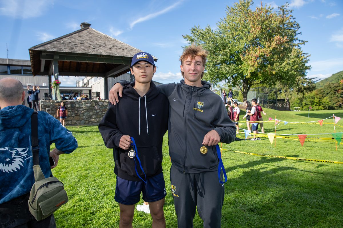 Two Storm King cross country runners show off their medals after a meet on campus