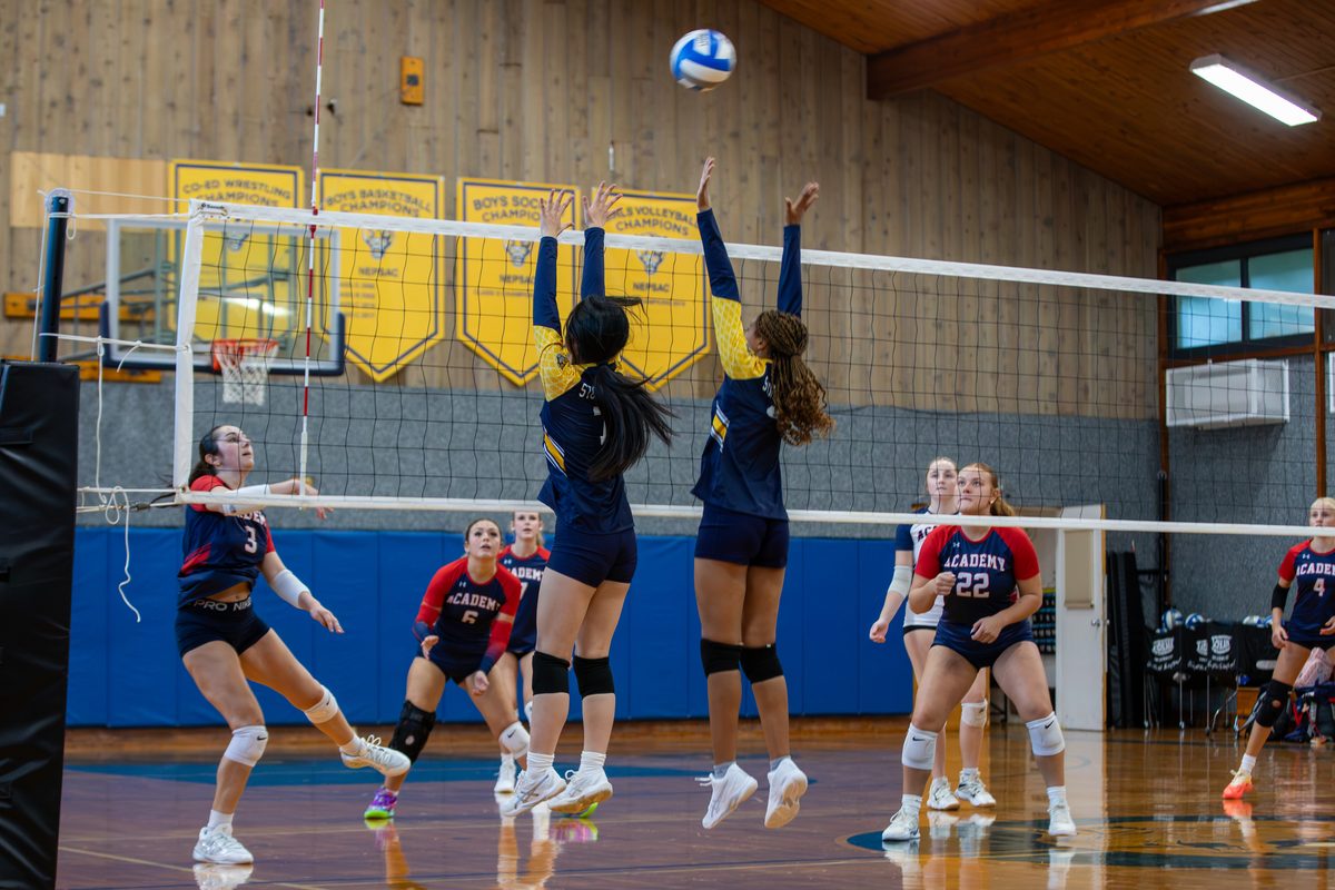 Two Storm King girls volleyball players rise together for a block at the net