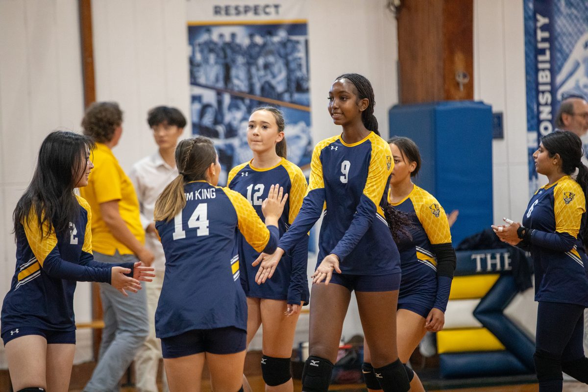 Storm King girls volleyball players exchange high fives between points in the Cougars gym